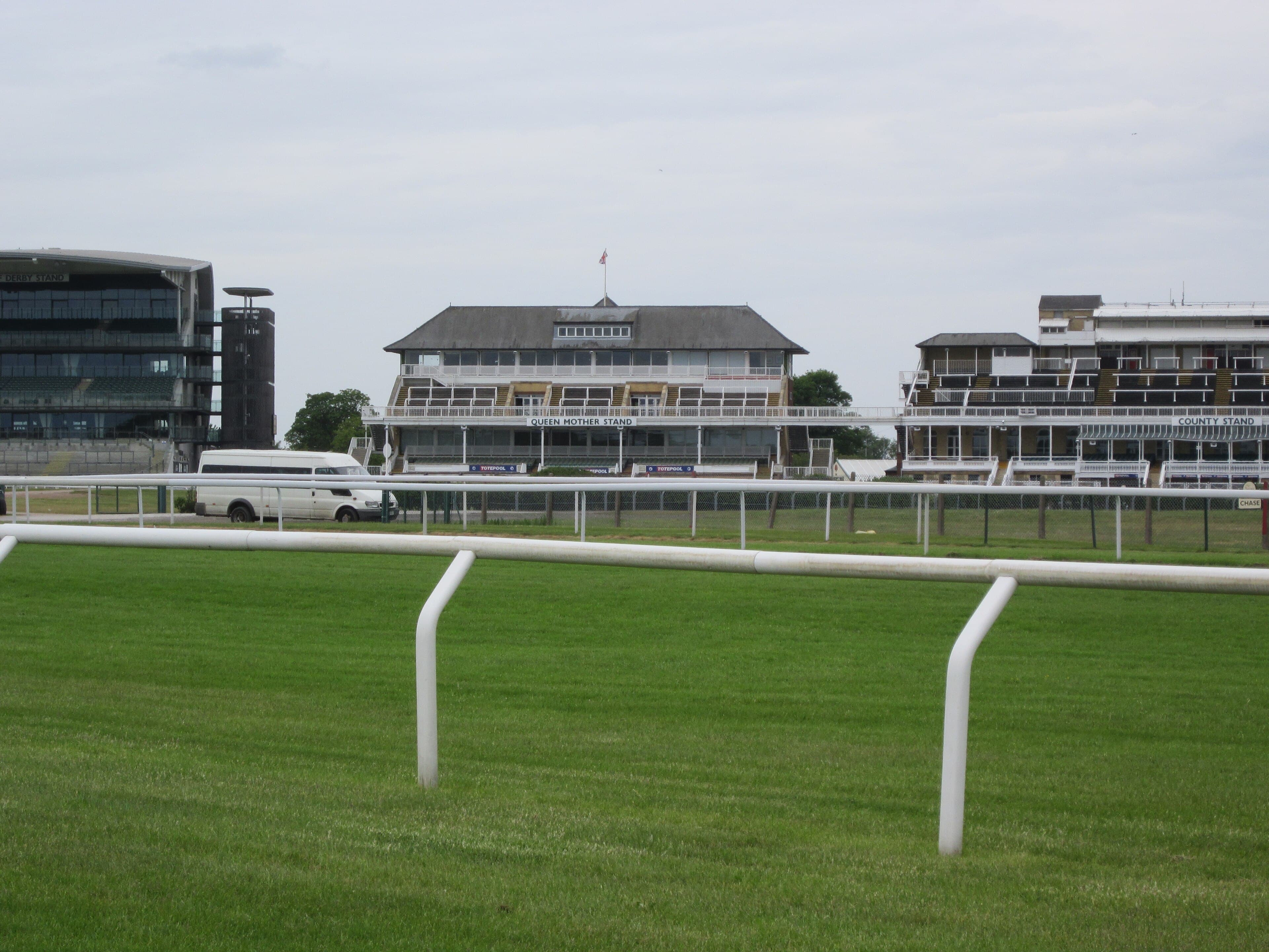 The Queen Mother and County stands at Aintree seen from across the course on a still summer morning.