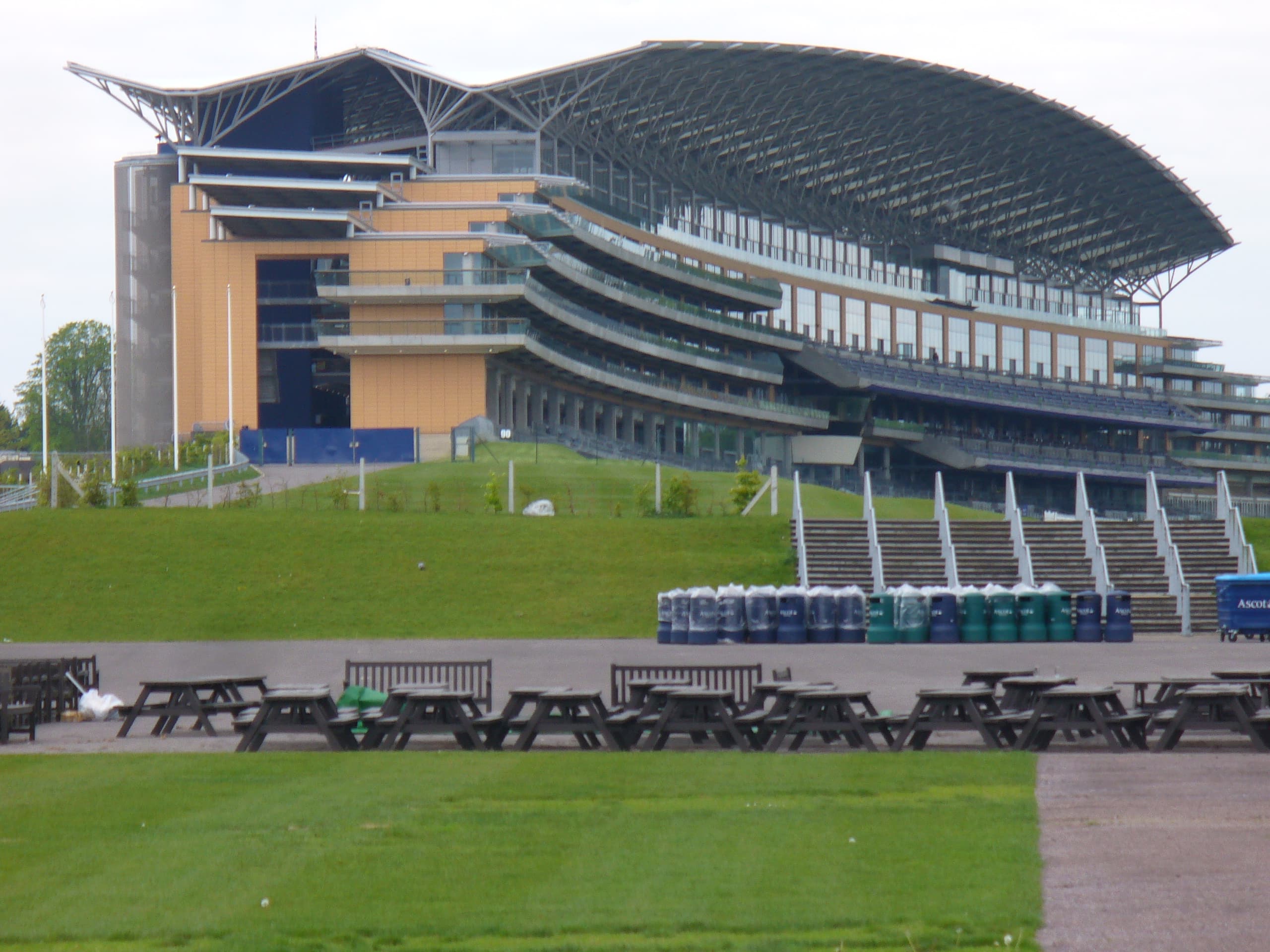 Ascot's grandstand rising above the lawns on a quiet day, picnic benches lined up in front.