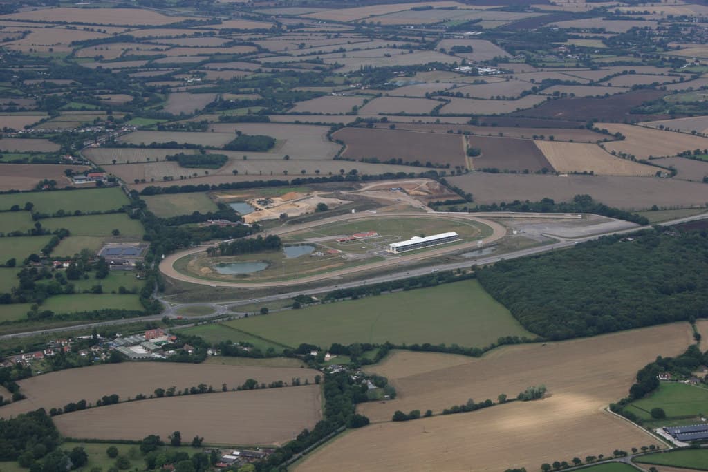 Aerial view of the oval at Great Leighs, now Chelmsford City Racecourse, set in Essex farmland with the grandstand along the home straight and the A131 running past.