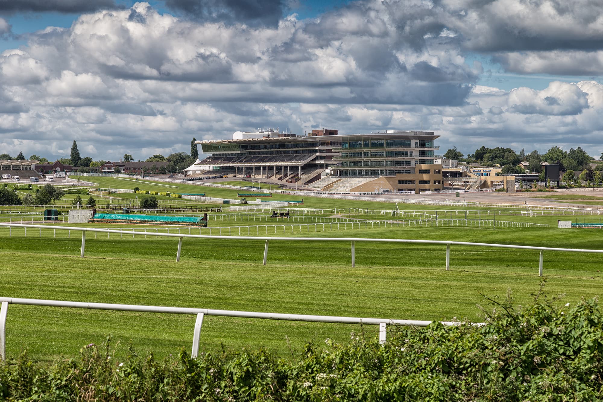 The Cheltenham grandstand across the empty course on a bright summer day.
