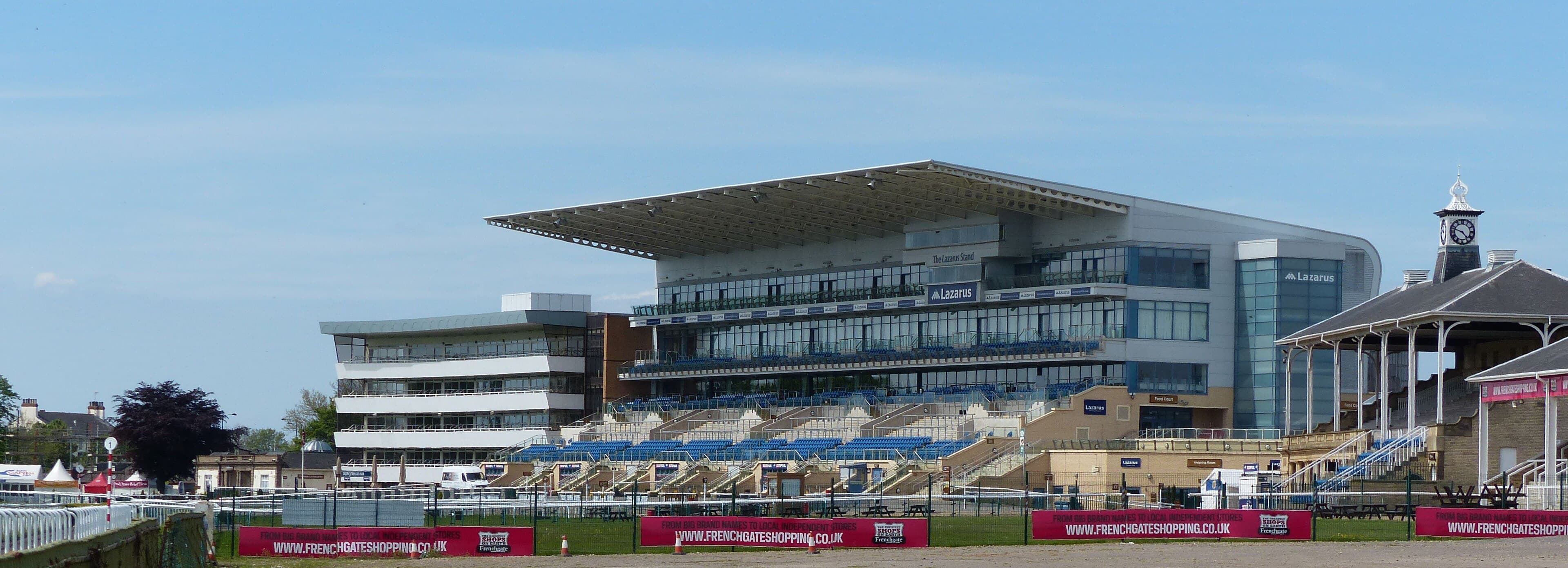 The Lazarus Stand at Doncaster with the old clock tower building beside it, seen across the running rail.