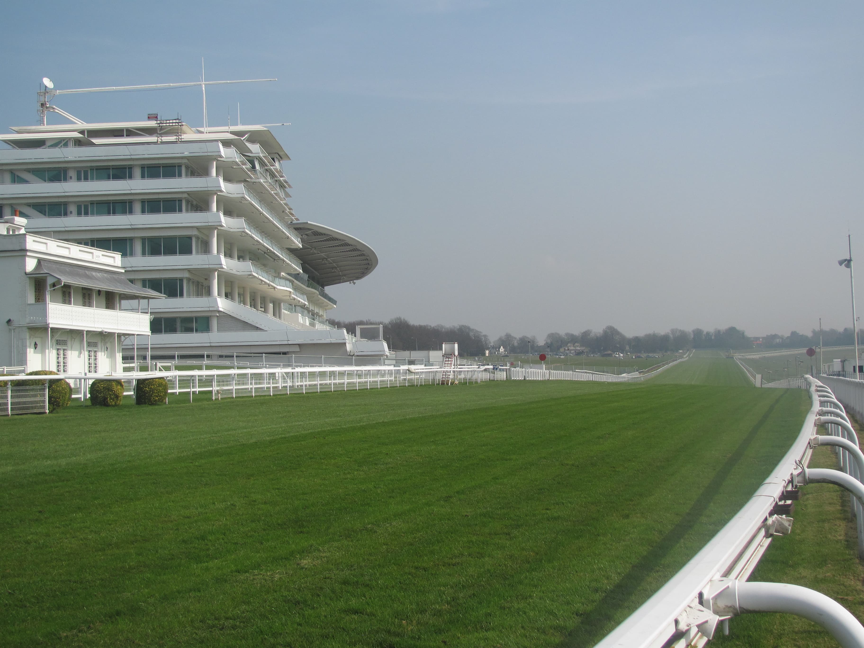 The Queen's Stand and the grandstand at Epsom beside the winning straight, the rail running away down the hill.