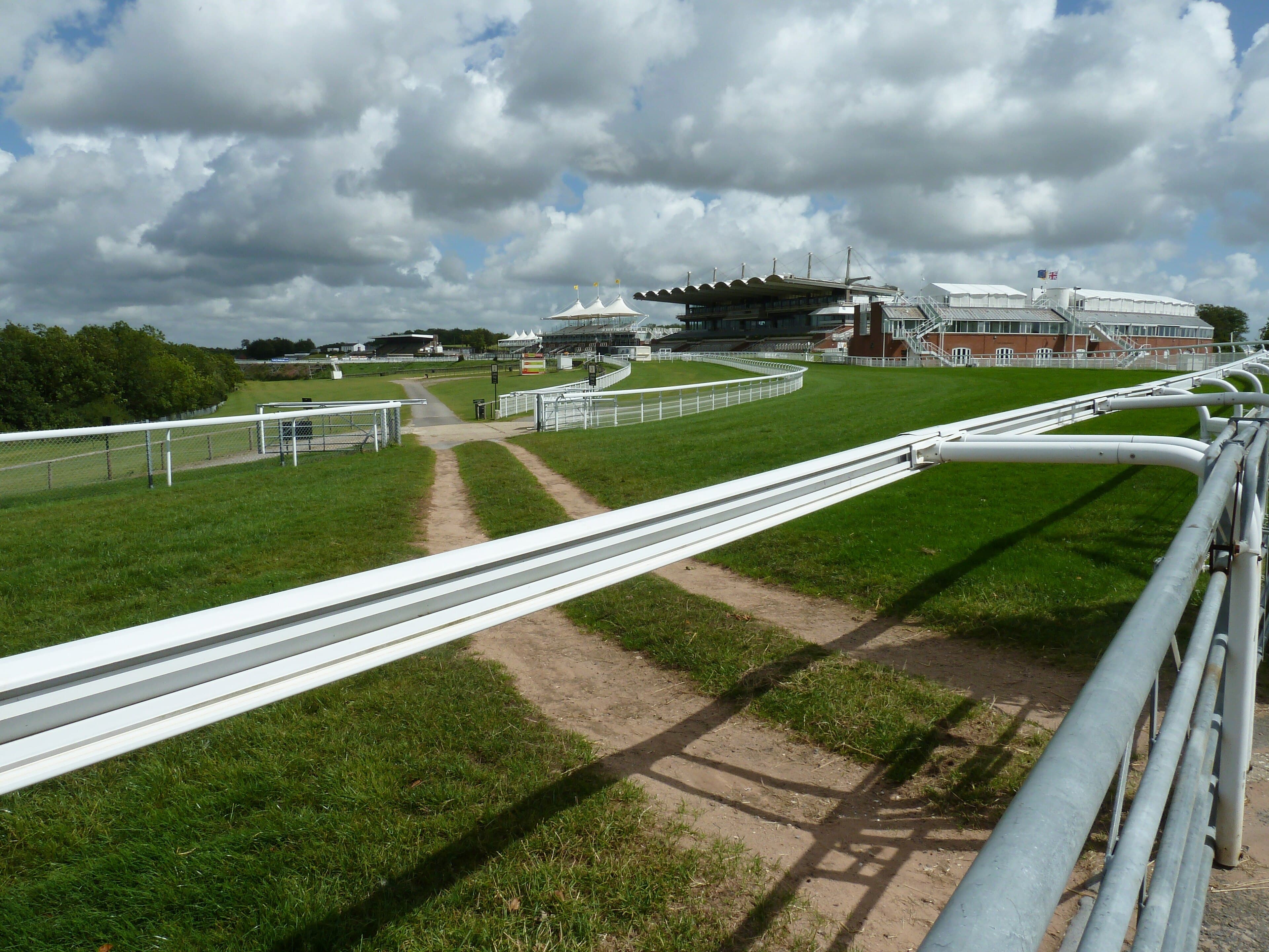The tented roof of the Goodwood grandstand across the turf, with cloud shadow running over the downs.