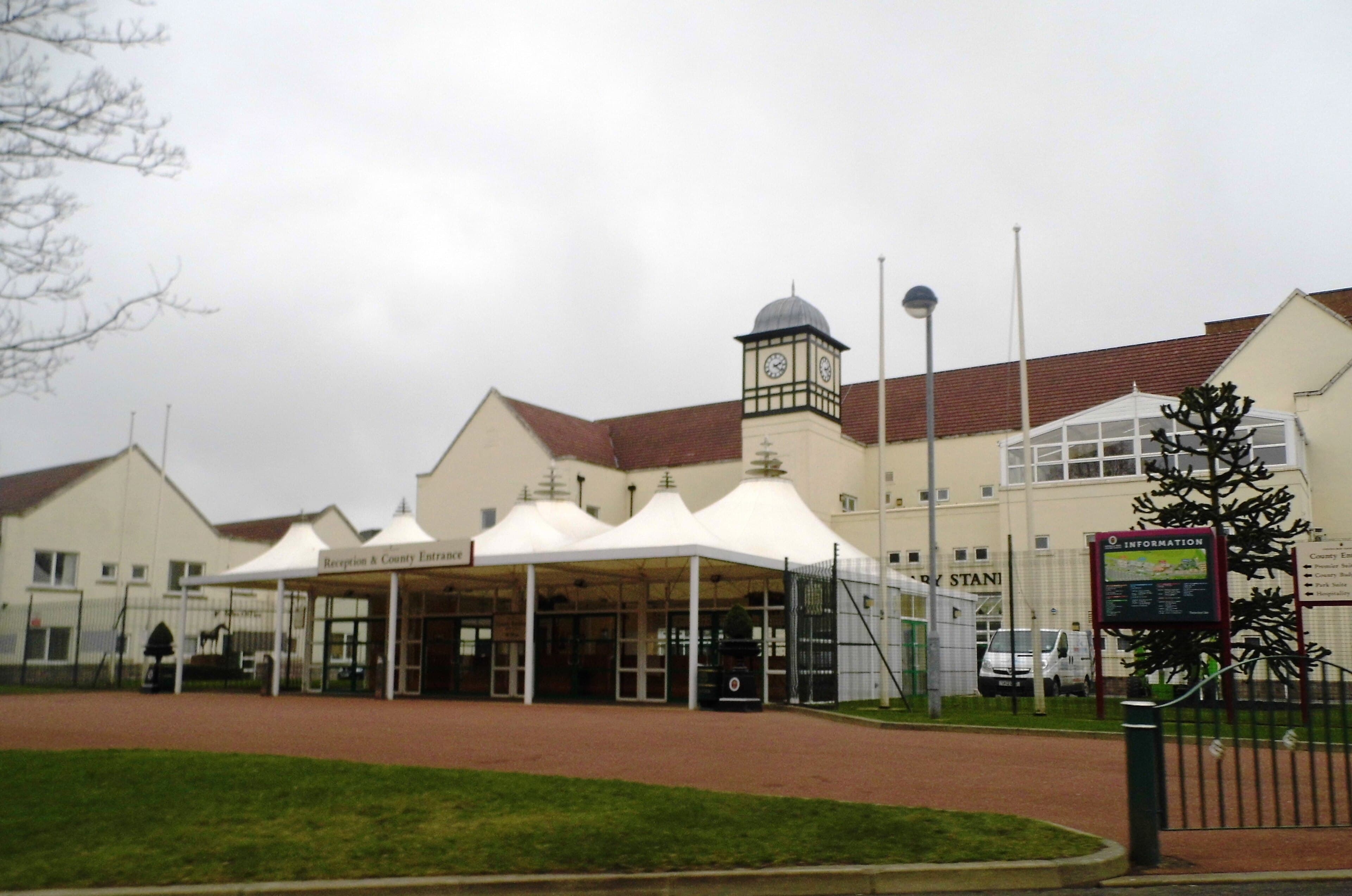 The reception and County entrance at Haydock Park, its clock tower and the Park Stand behind the canopies.