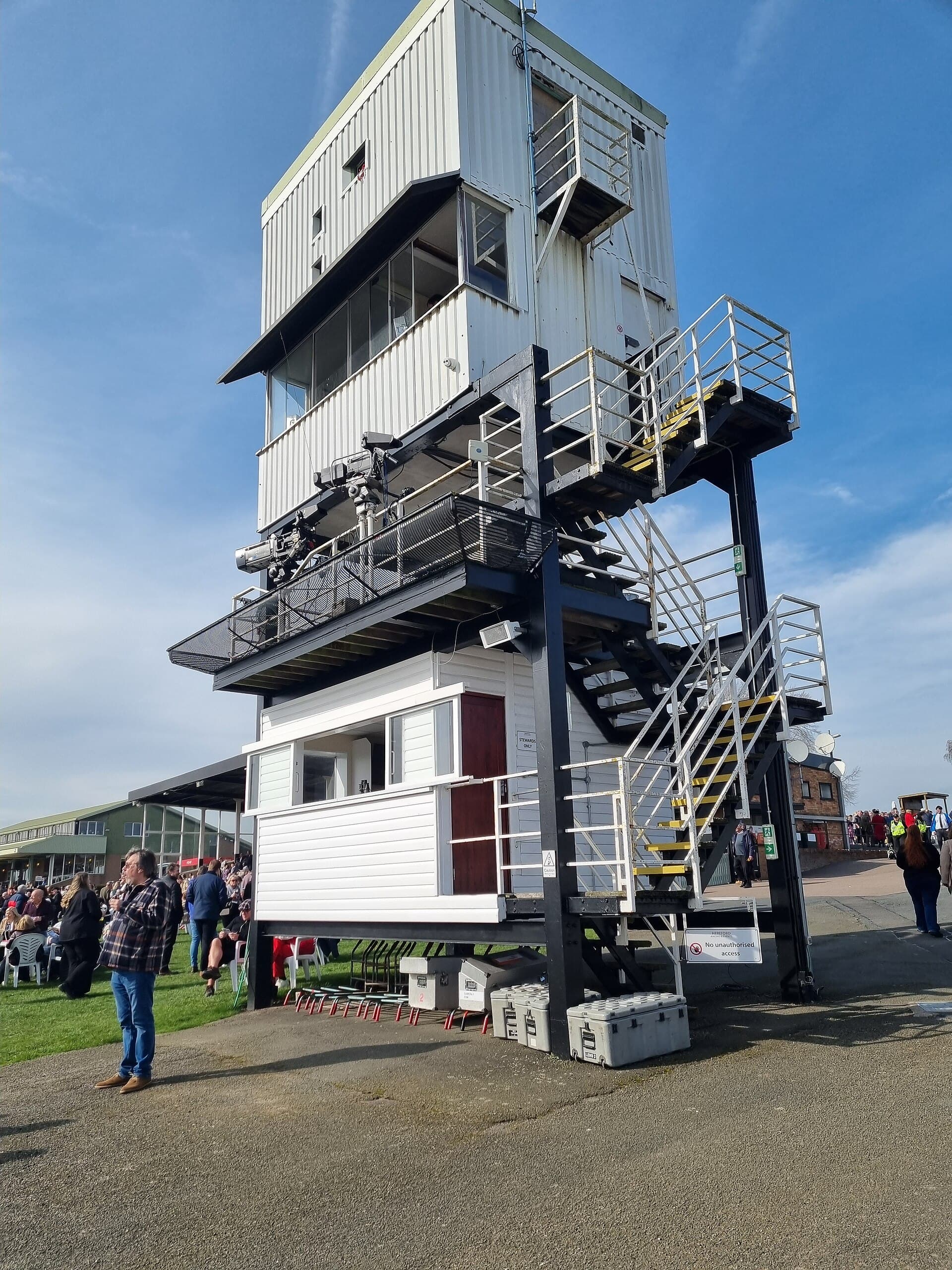 Hereford's stacked white judges' and commentary tower seen from below, with its external staircase, camera platform and the green stand behind.