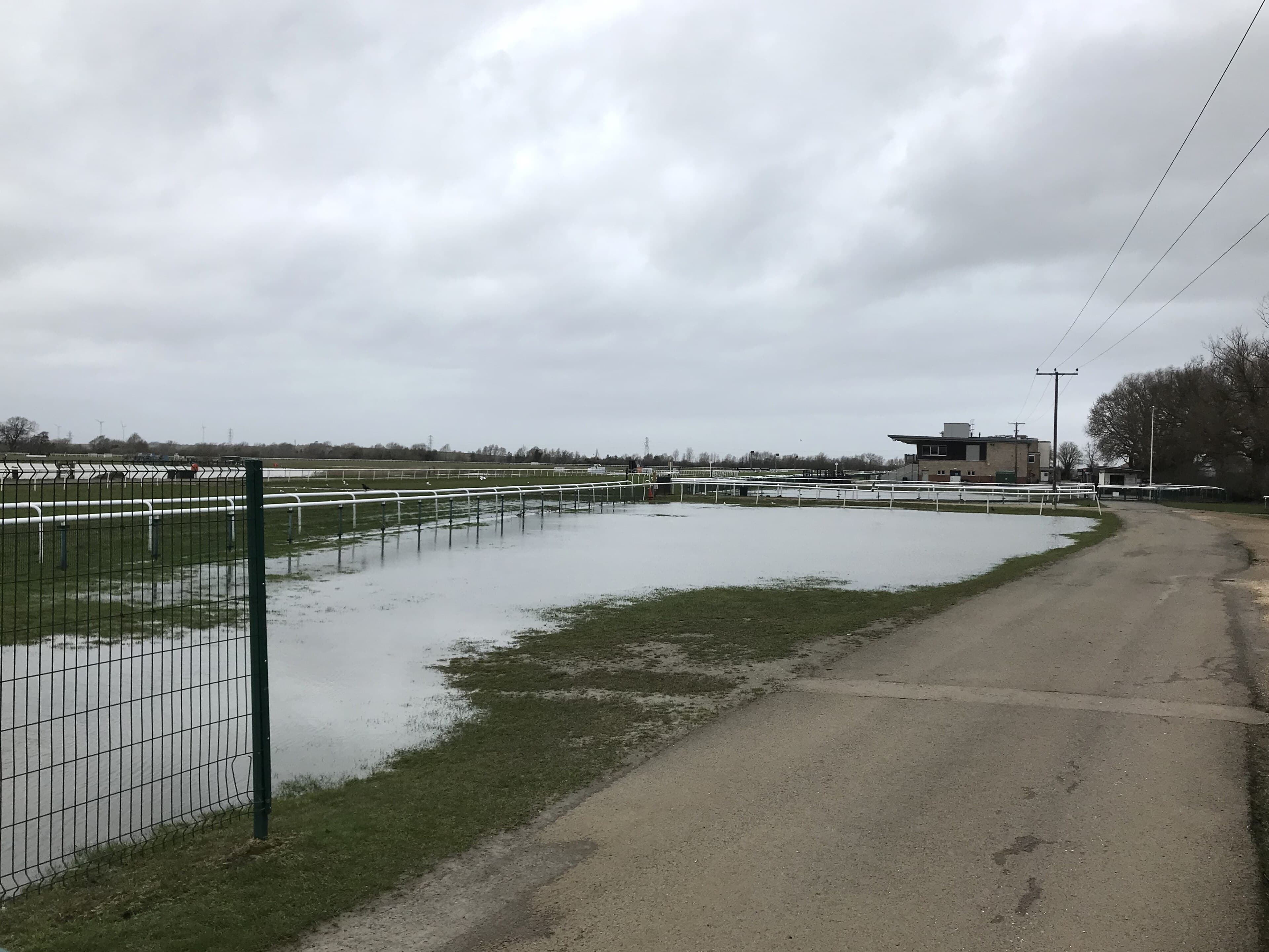 Standing water on the inside of the track at Huntingdon under a heavy grey sky, the stewards' box and stands away to the right