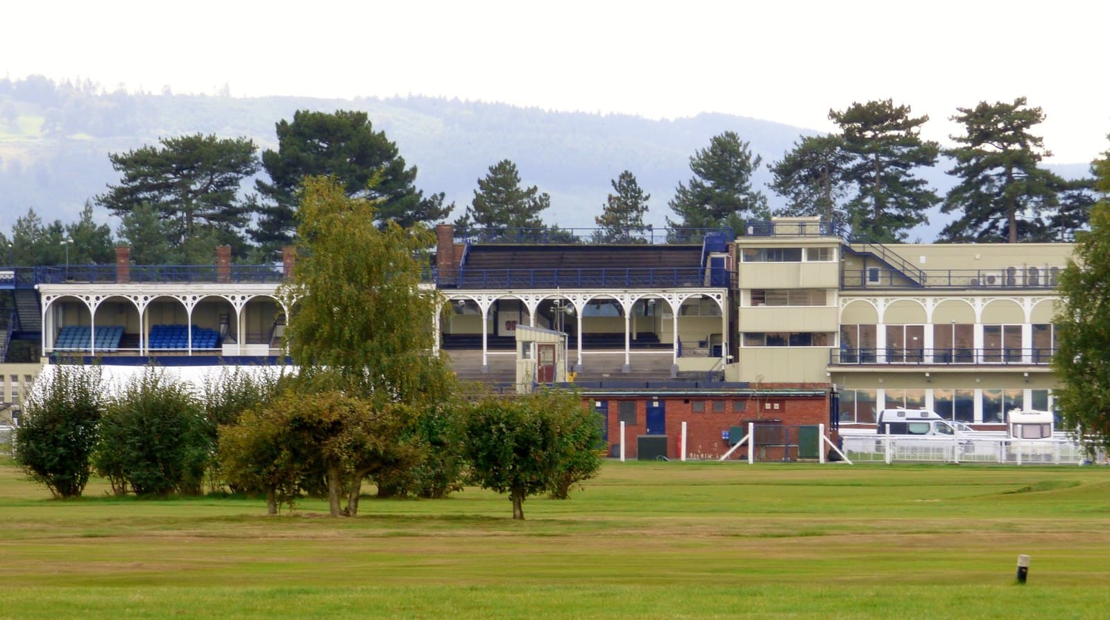 The old main stand at Ludlow Racecourse, its ironwork canopy and tiered seating seen across the grass from the far side of the track.