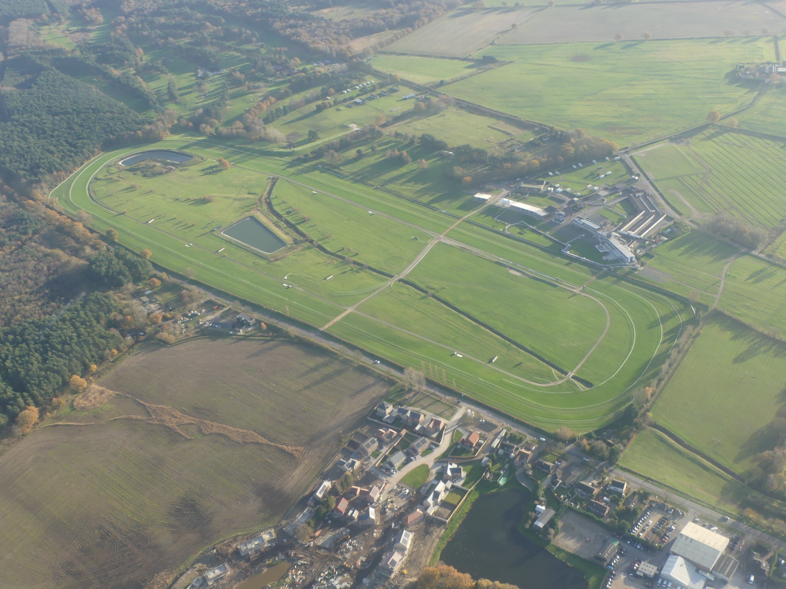 Aerial view of Market Rasen racecourse and the eastern edge of the town, with the jumps circuit, the lakes inside the course and the stands laid out below