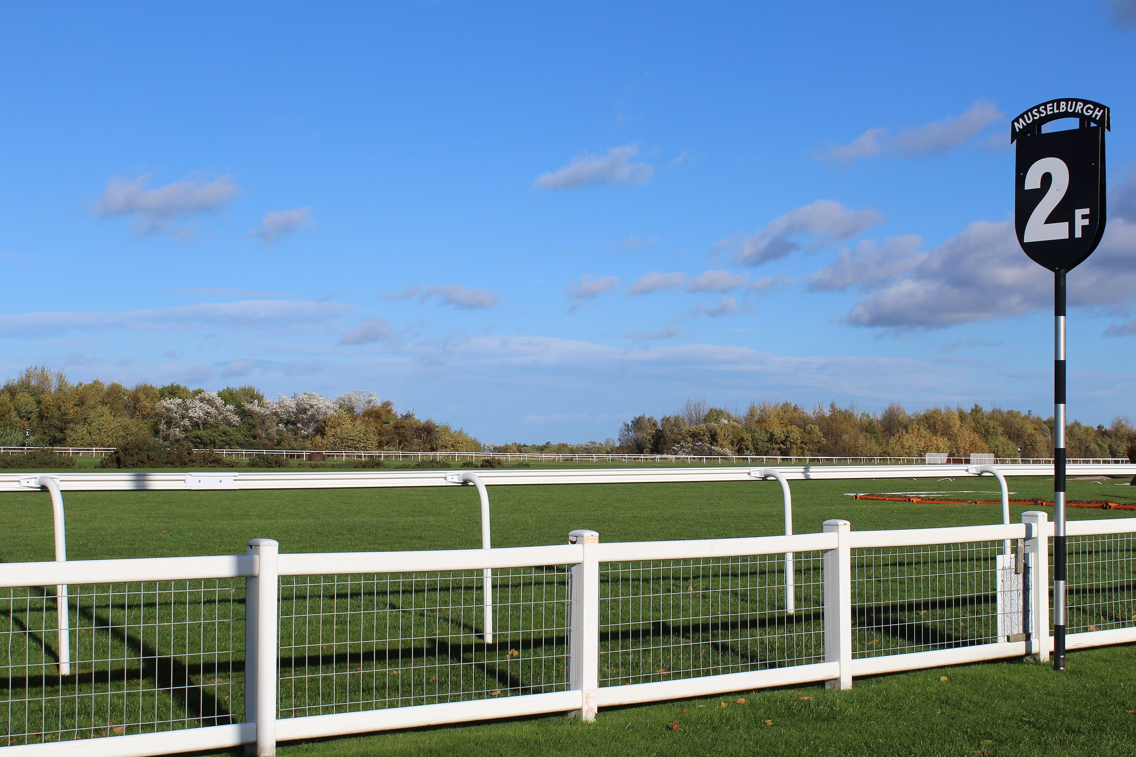 The two-furlong marker beside the running rail at Musselburgh racecourse under a bright autumn sky.