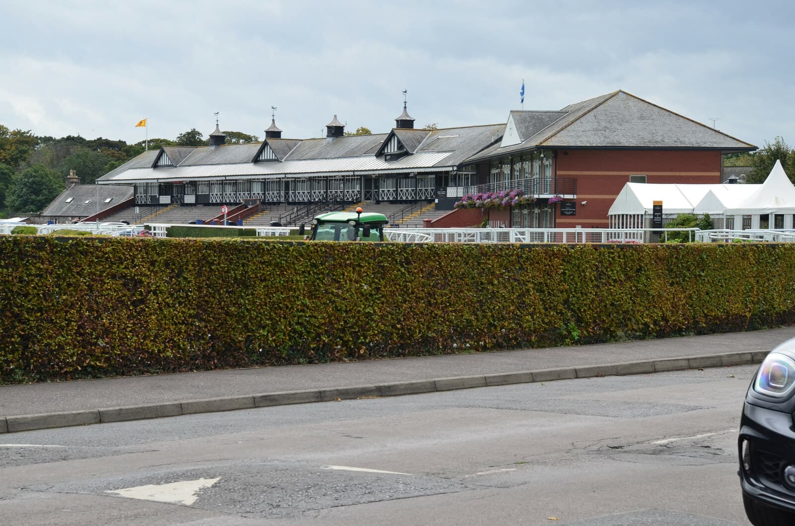 The grandstand at Musselburgh racecourse behind a clipped hedge, a long white building with dormer windows.