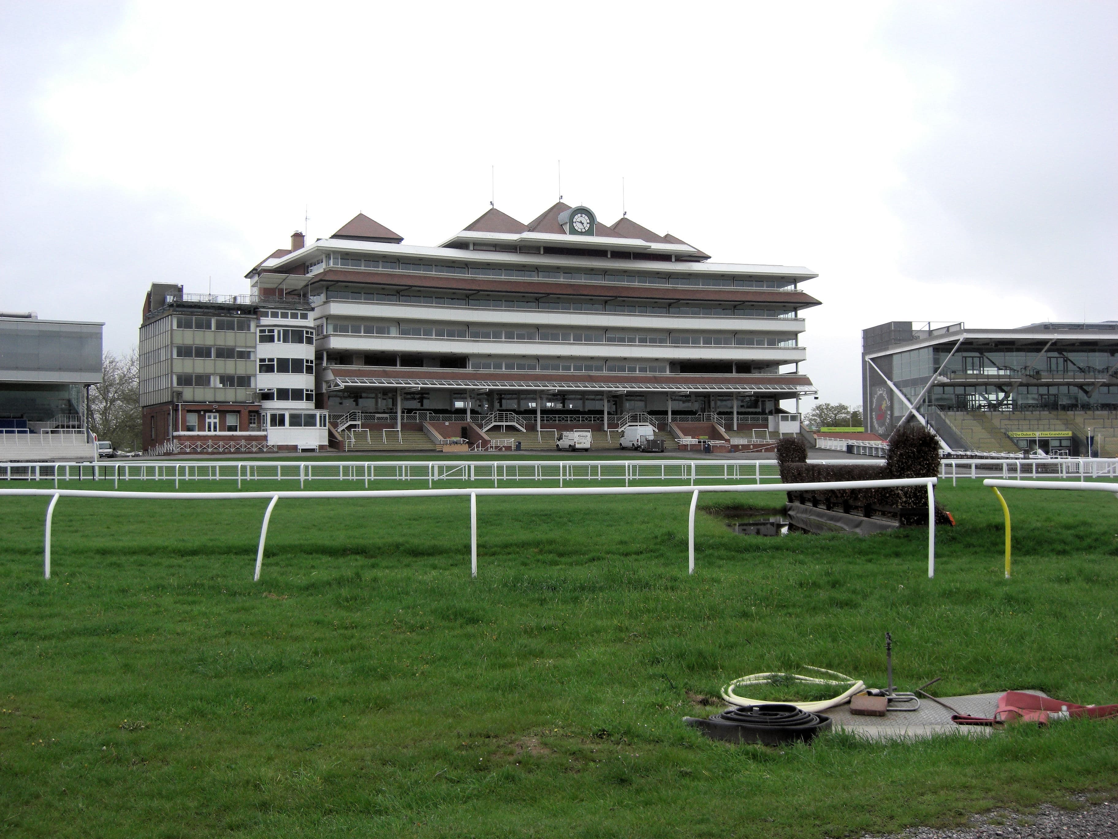 The main stand at Newbury seen across the track, with the water jump and running rails in front.