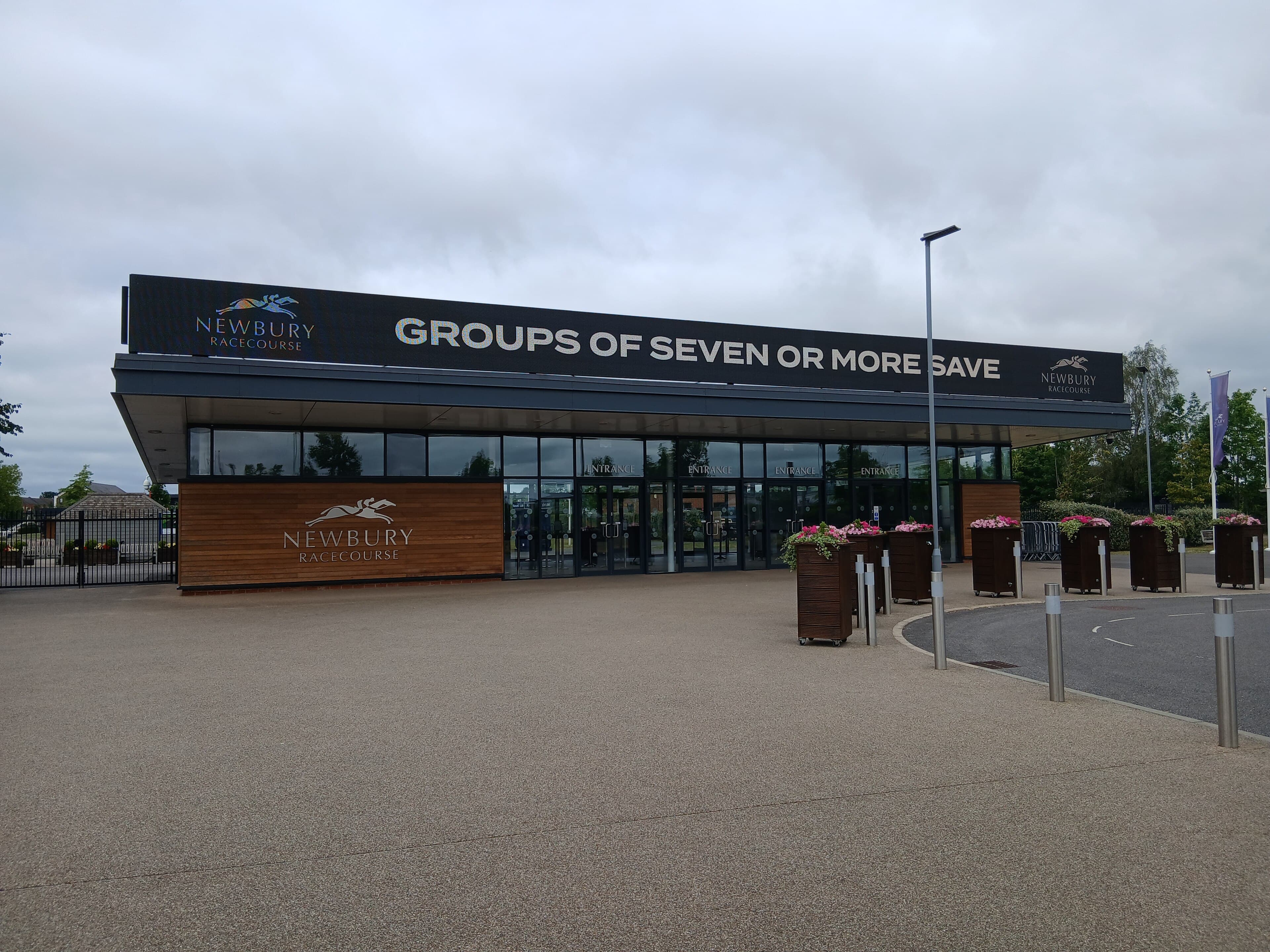The Newbury Racecourse entrance building, its long dark fascia carrying the course name above the doors.
