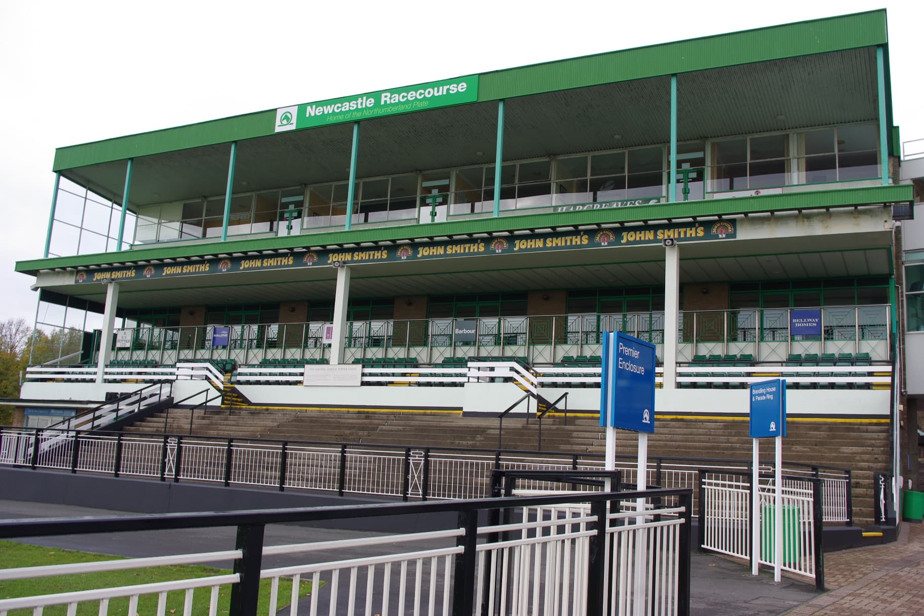 The main grandstand at Newcastle Racecourse seen from the rail, its green fascia carrying the course name.