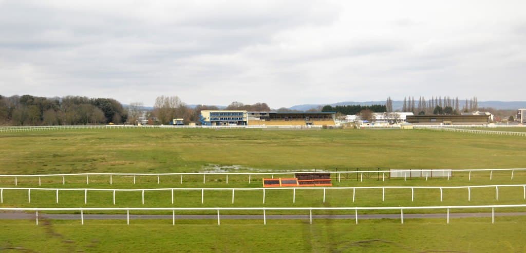 A wide view across the Newton Abbot track towards the stands, running rails in the foreground.