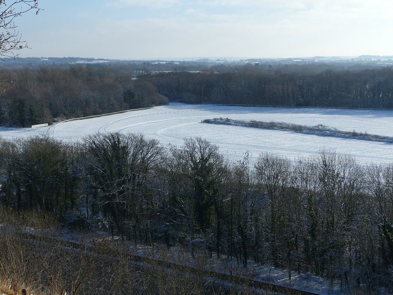 Nottingham Racecourse under snow, seen from the high ground at Colwick Woods with the bend picked out in white.