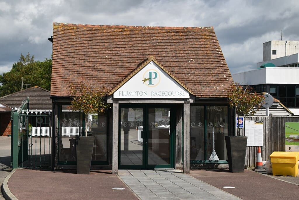The weatherboarded ticket office at Plumpton Racecourse, the course name and P monogram above the doors.