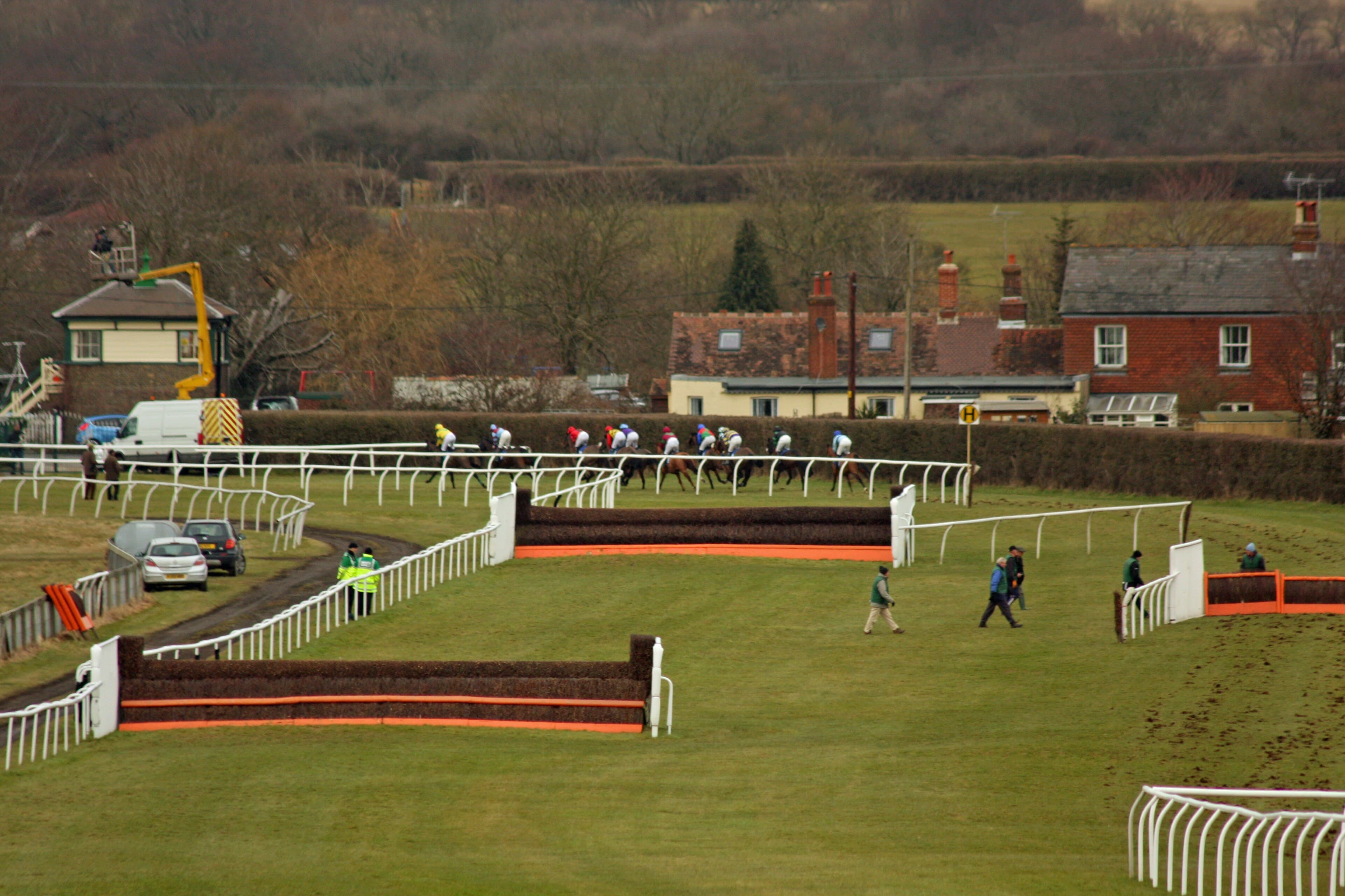 Two birch chase fences with orange take-off boards on the far side at Plumpton, the field passing along the hedge line behind.