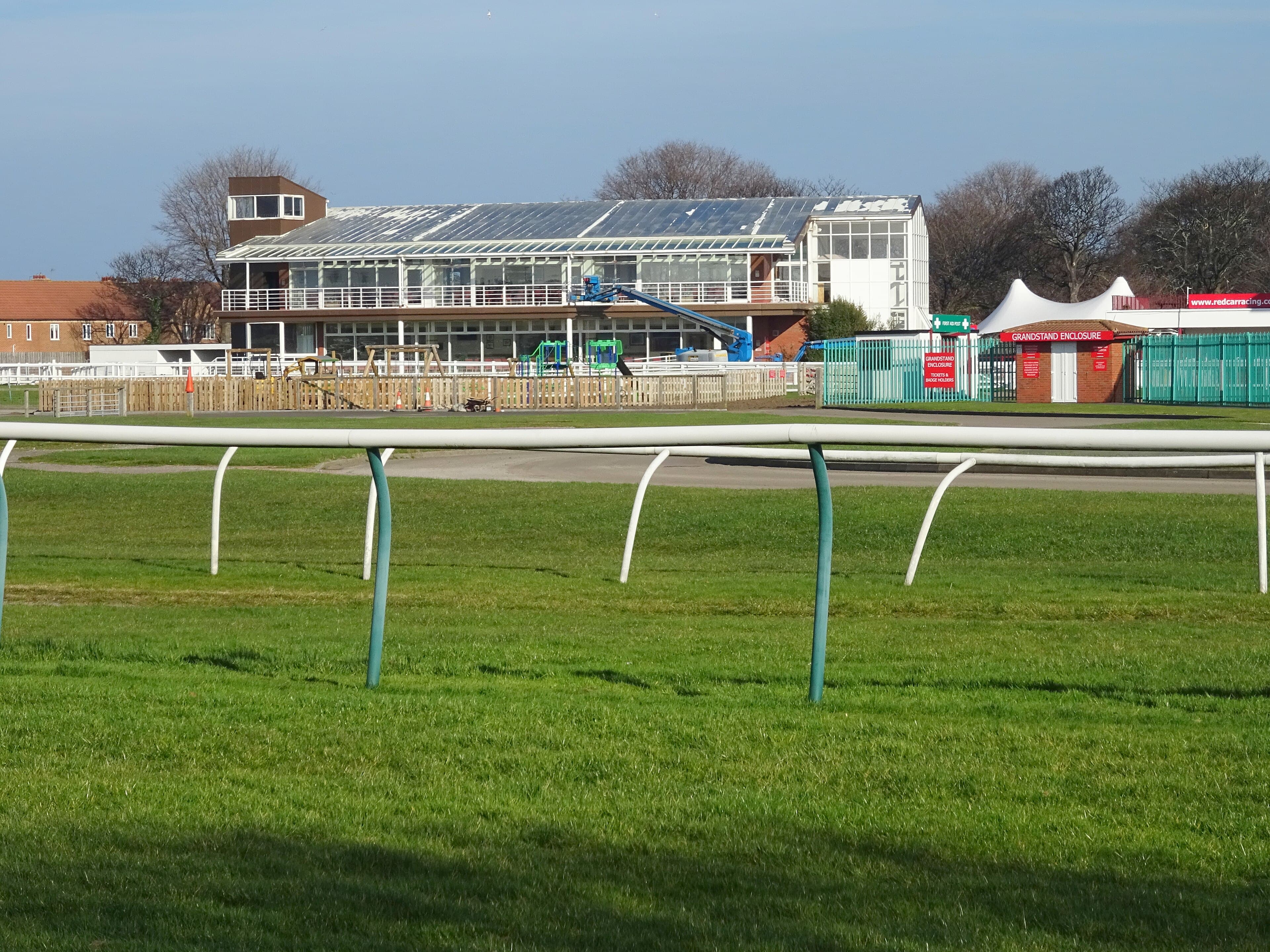 The glass-fronted stand at Redcar seen across the running rail from the course side.
