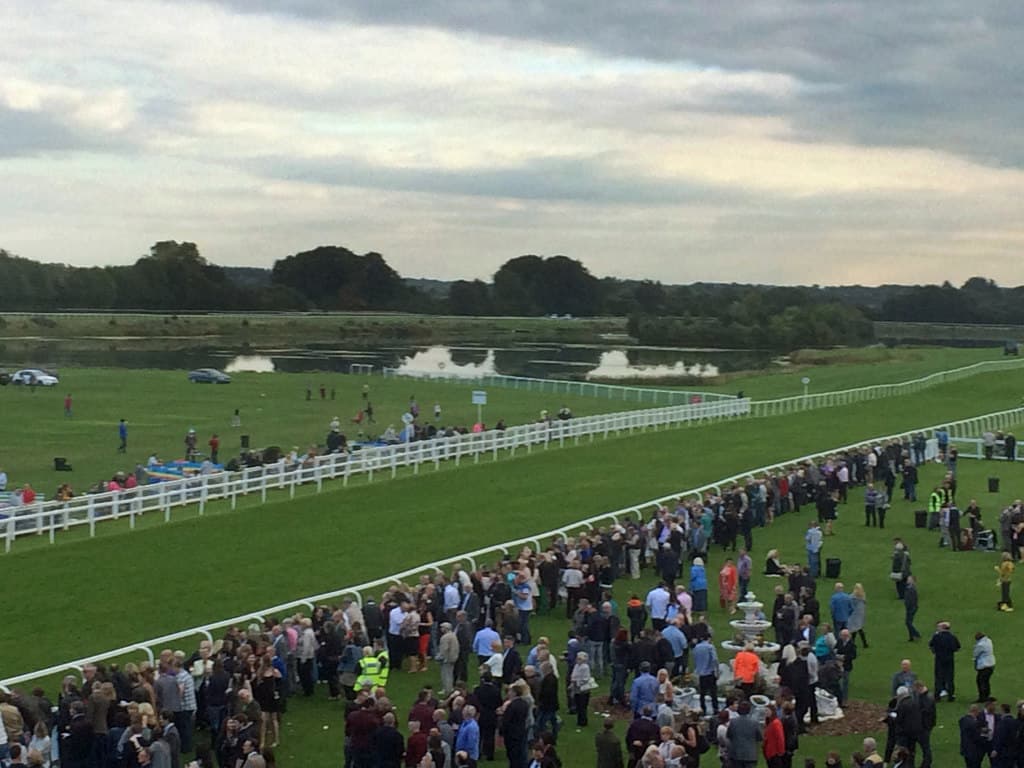 Racegoers lining the rail at Ripon on the last day of the season, the course running away to flooded fields.