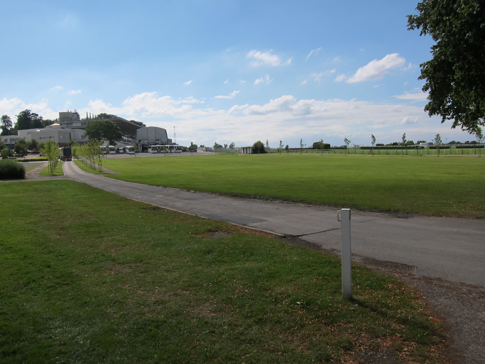 The inside of the Sandown Park course on a bright summer day, the service road running beside the turf.