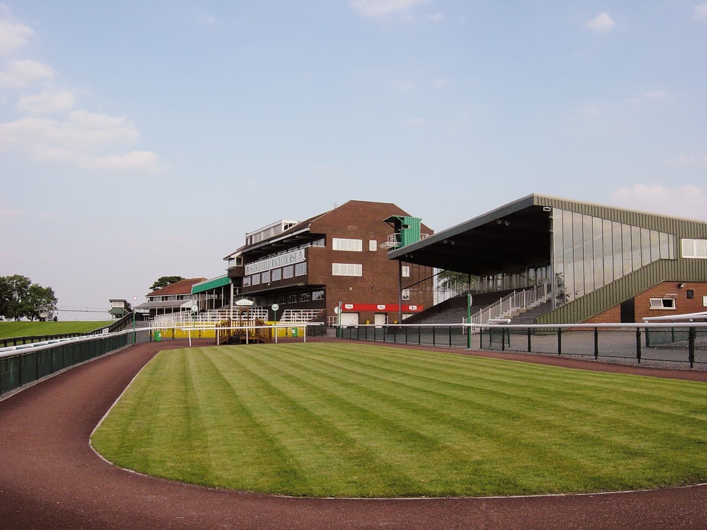 The grandstands at Sedgefield seen across the striped parade-ring lawn and the horsewalk.