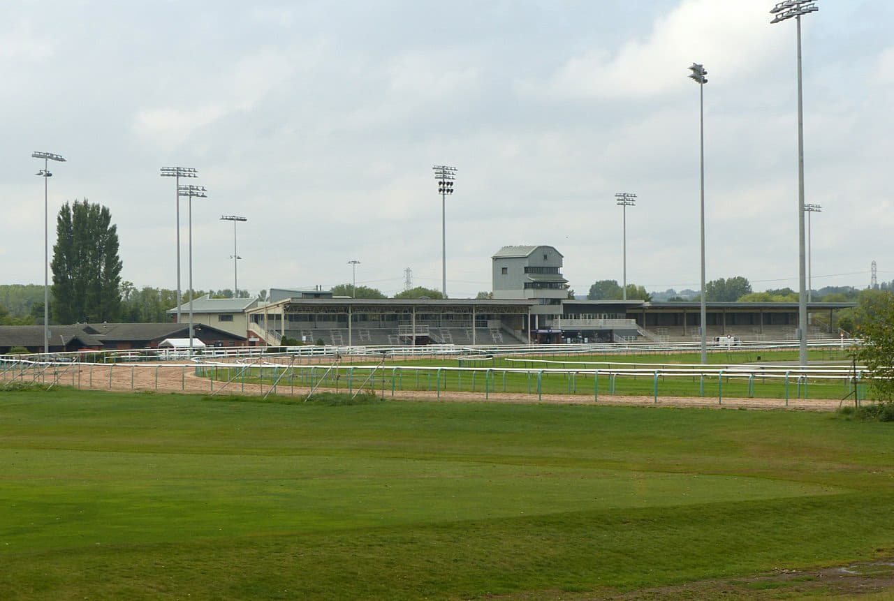 The stands at Southwell across the sand track, floodlight pylons standing over the back of the course.
