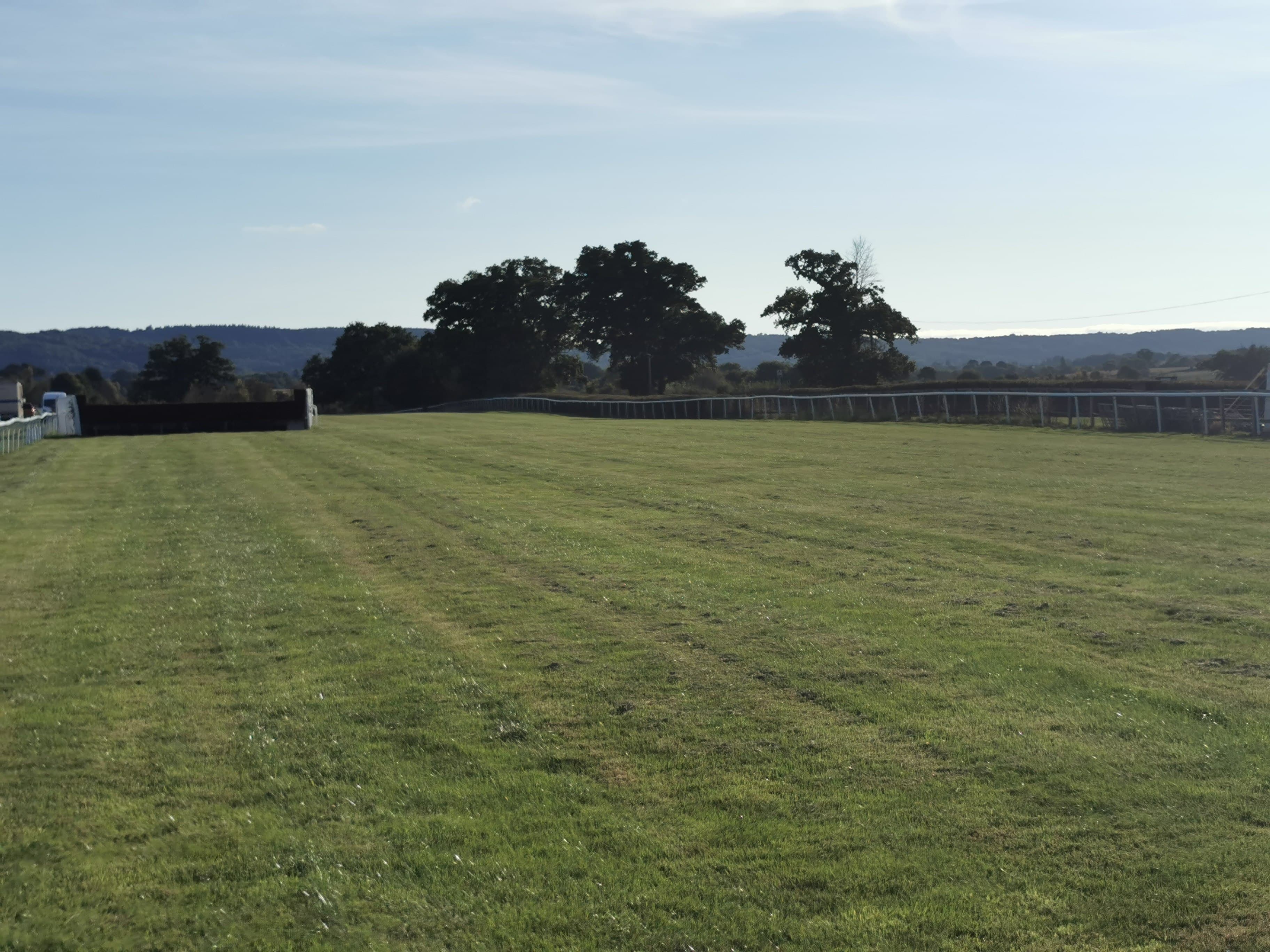 The far side of Taunton Racecourse in low autumn sun, the boundary hedge and the hills beyond.