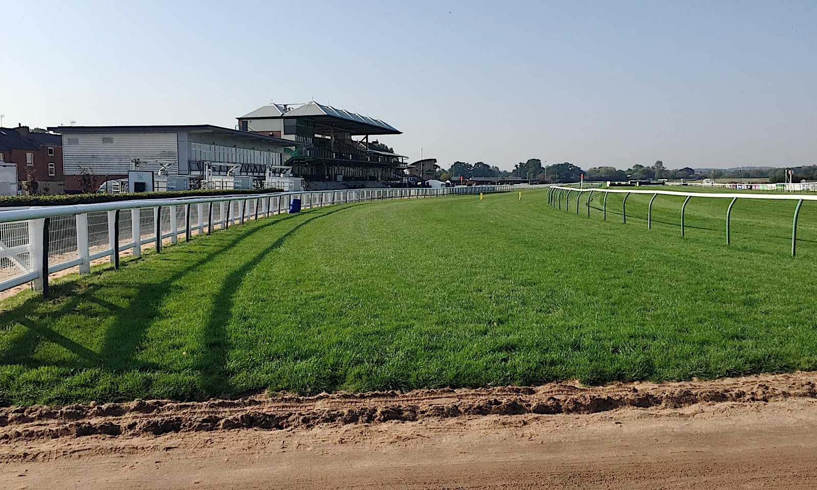 Warwick Racecourse back in use after track works, fresh turf inside the rail and the stands along the far side.