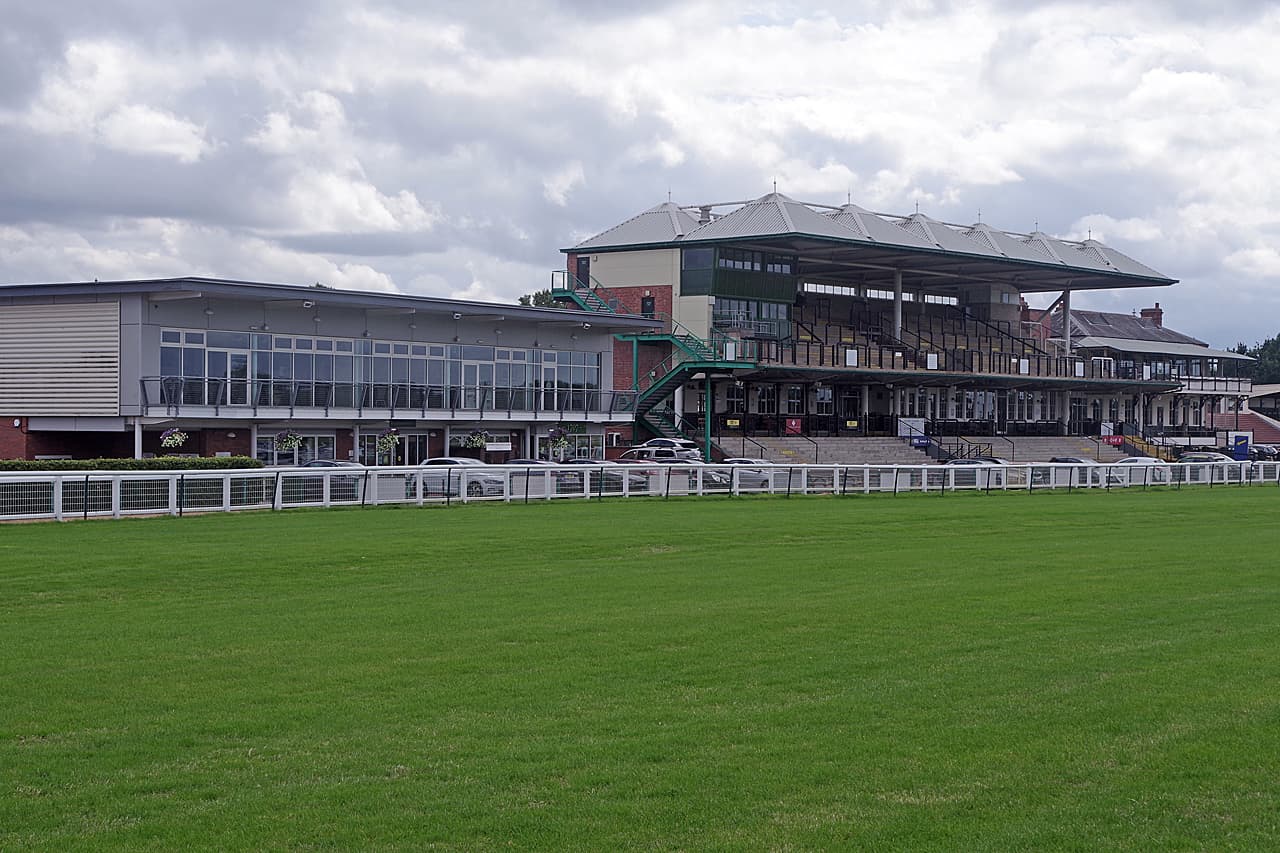 The stands at Warwick Racecourse across the home straight, the glass frontage running the length of the enclosure.