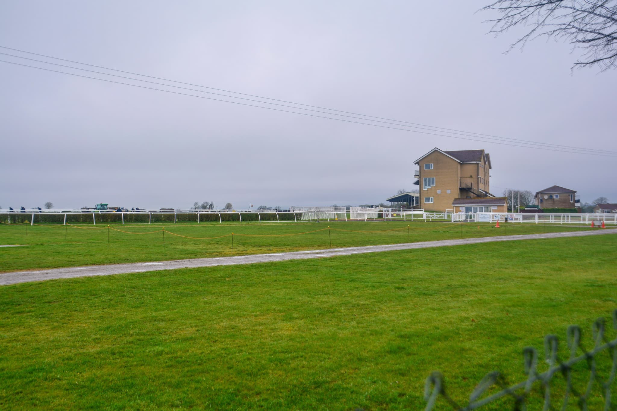 The track at Wincanton racecourse on a grey winter day, with the white running rails and the stone-built stand beyond.